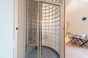 A room with a glass partition, a tiled floor, and a table with chairs. - Villa Il Guardingo in Rio Elba (Rio Nell'Elba)
