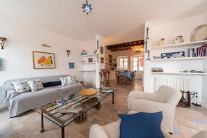 Un salon comprenant un canapé, un fauteuil, une table basse et un coin repas avec des chaises et une table.