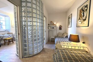 A bedroom with a bed, a lamp, a chair, a desk, and a glass partition. - Villa Il Guardingo in Rio Elba (Rio Nell'Elba)