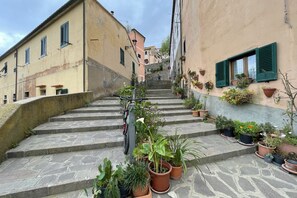 A narrow stone staircase leading up to a building with multiple windows and potted plants. - Villa Il Guardingo in Rio Elba (Rio Nell'Elba)