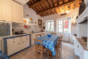 Une cuisine avec un plan de travail carrelé, des meubles en bois, une cuisinière et une table à manger avec des chaises.