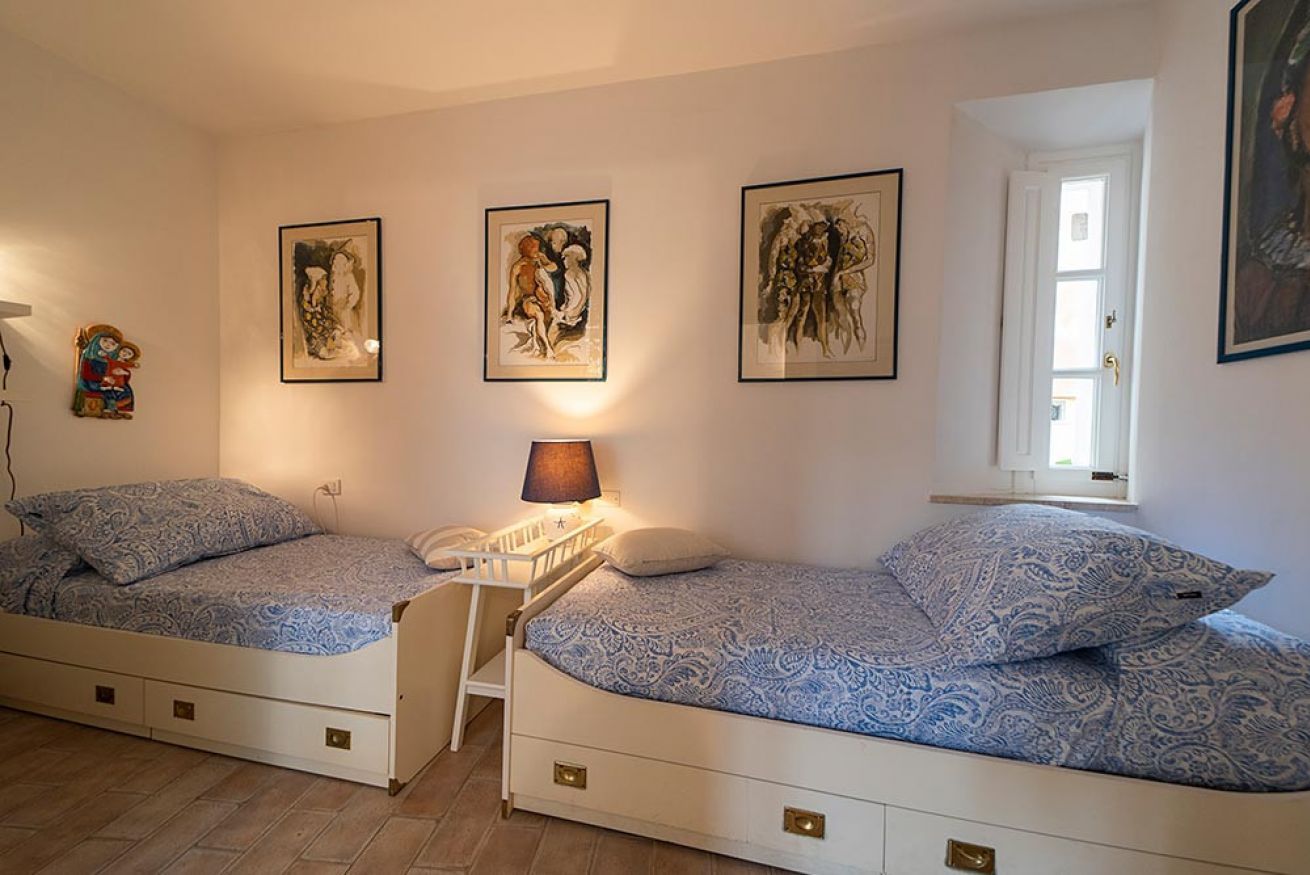 A bedroom with two beds, a nightstand, a lamp, and wall art.