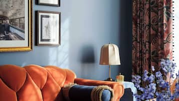 Quarto com parede azul, sofá, quadros emoldurados, abajur e uma estatueta de tigre decorativa.