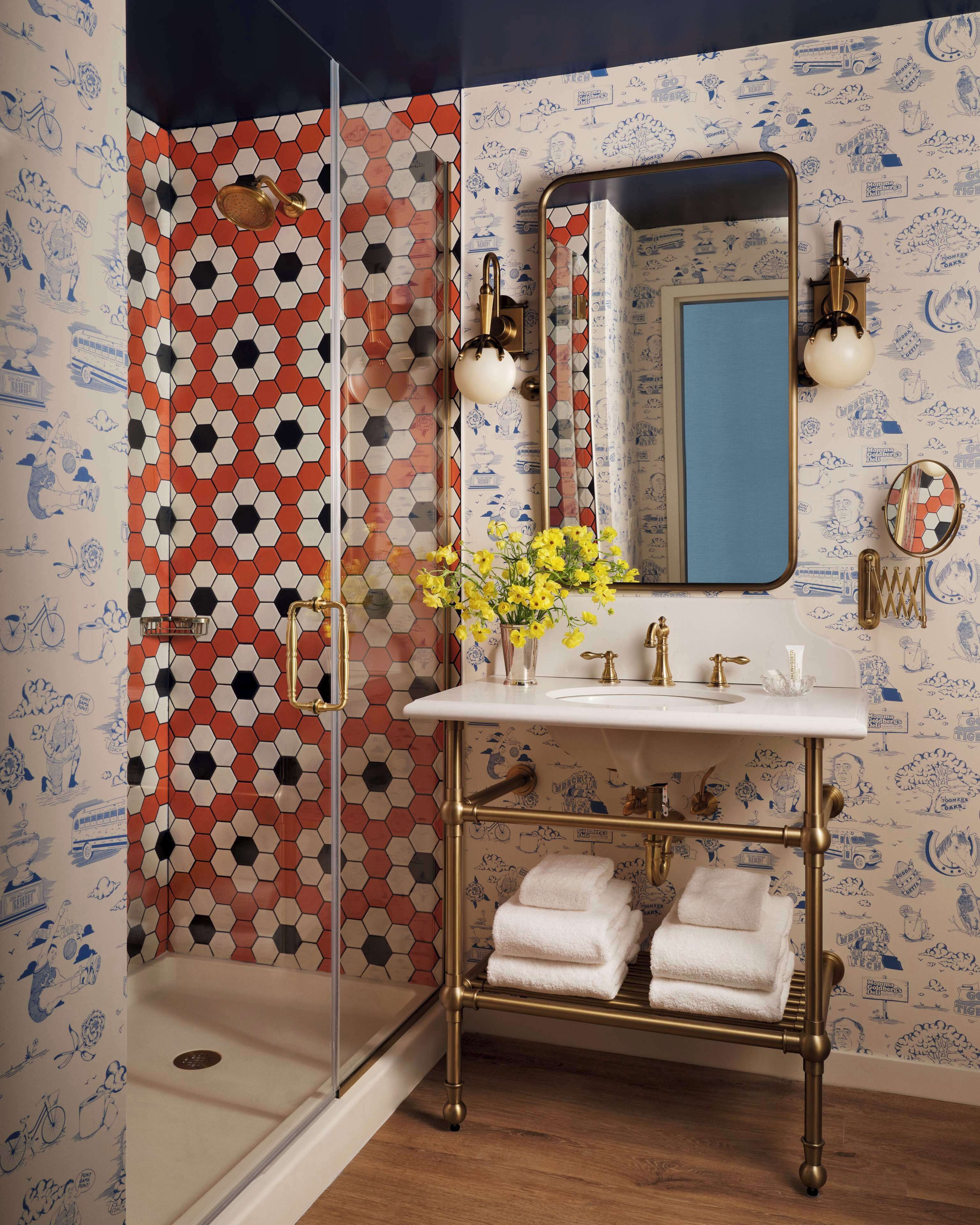 A bathroom with a shower, a sink with a mirror, and towels.