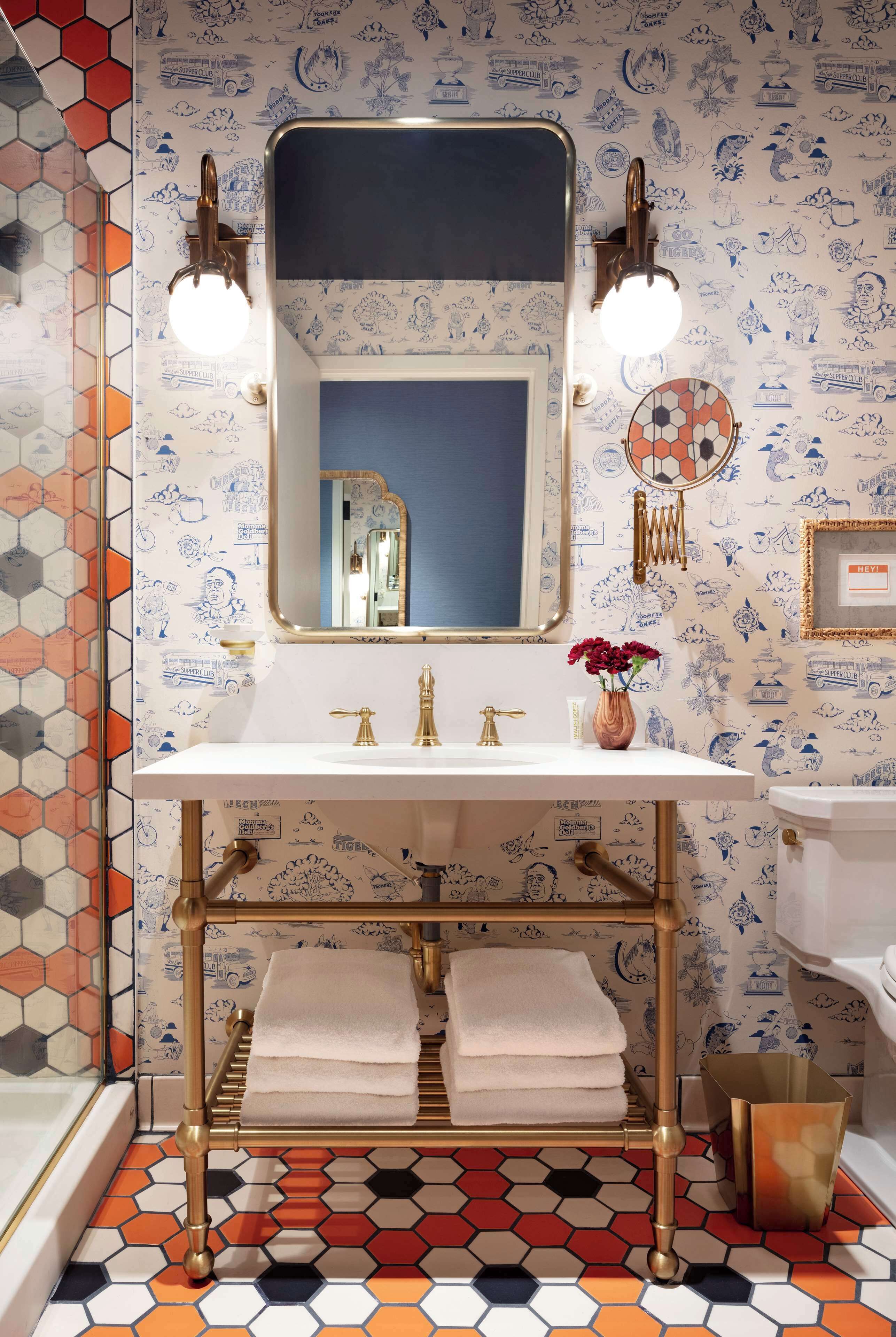 A bathroom with a white sink, gold fixtures, and a mirror with lights.