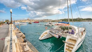 A marina with boats docked, a cityscape in the background, and a clear sky. - Roof terrace, Seaview 3 bedroom penthouse GOSLM-11 (Sliema)