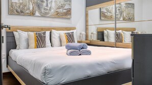 A modern bedroom with a large bed, a wooden headboard, and a large mirror. - Roof terrace, Seaview 3 bedroom penthouse GOSLM-11 (Sliema)