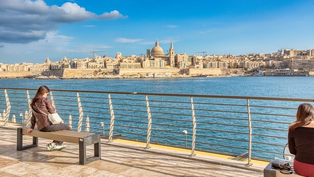 A waterfront promenade with benches overlooking a cityscape and a body of water. - Roof terrace, Seaview 3 bedroom penthouse GOSLM-11 (Sliema)