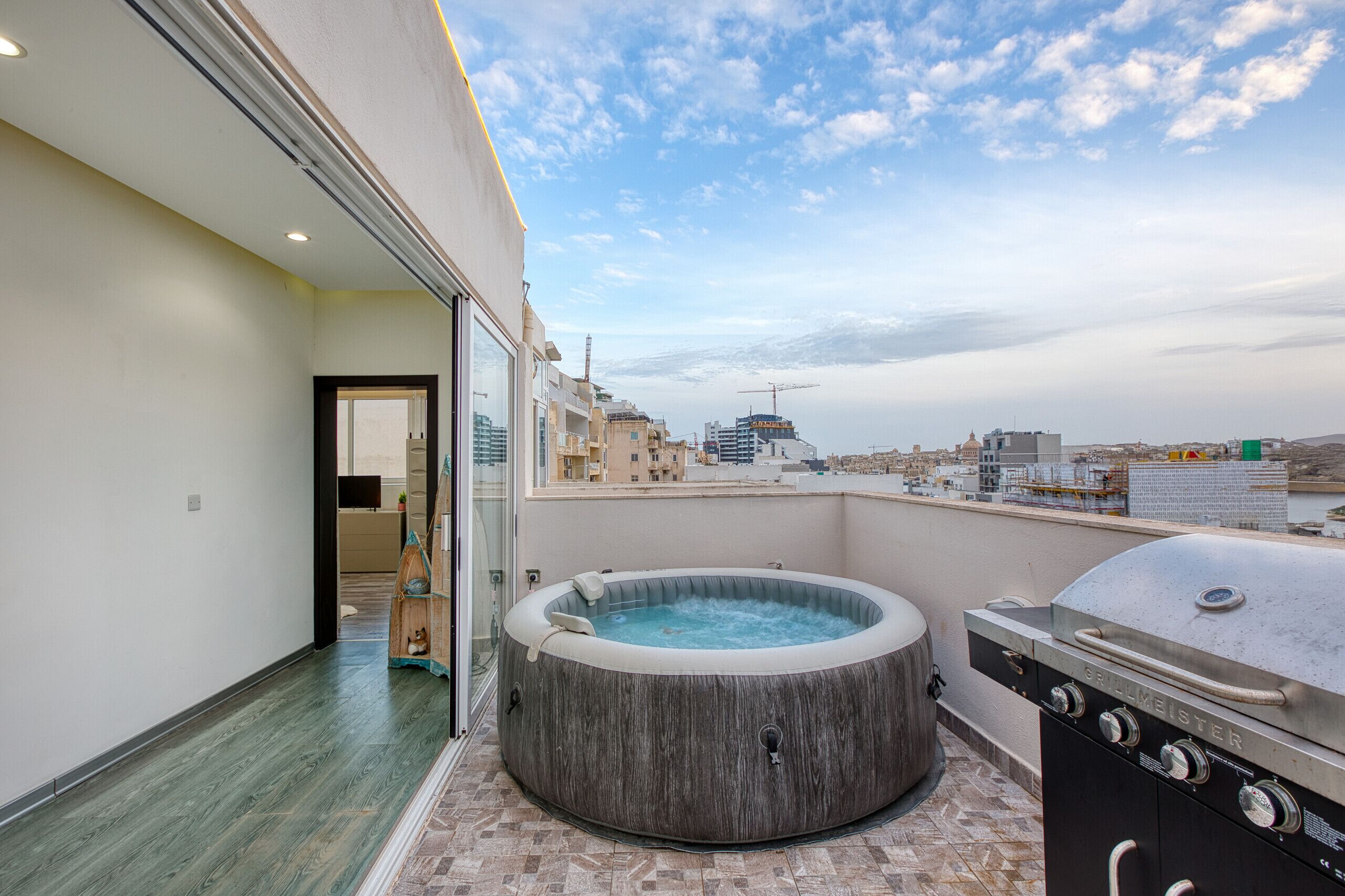 Una terrazza sul tetto con vasca idromassaggio, barbecue e vista sulla città.