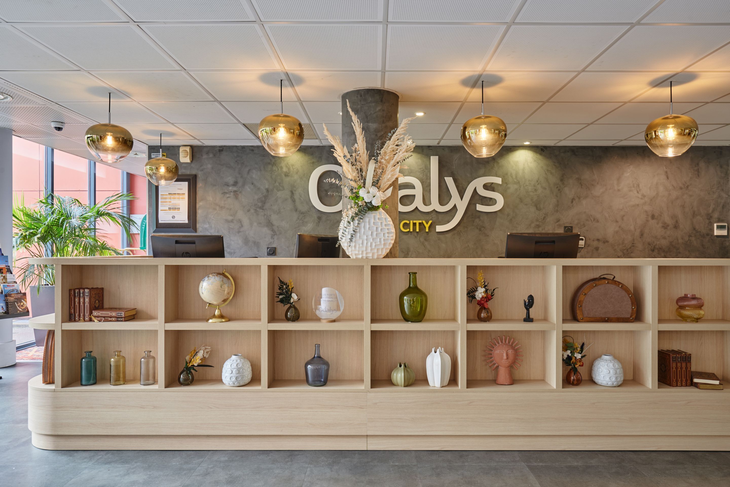 A reception area with a wooden reception desk, a large sign reading "Calyys City", and various decorative items on shelves.