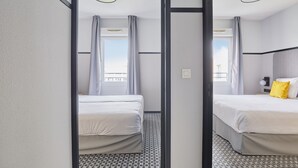 Ein Hotelzimmer mit zwei Betten, Blick auf die Stadt und modernem Design.