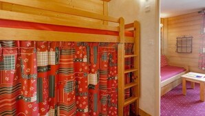 A cozy room with a bunk bed, a wooden ladder, and a small table.