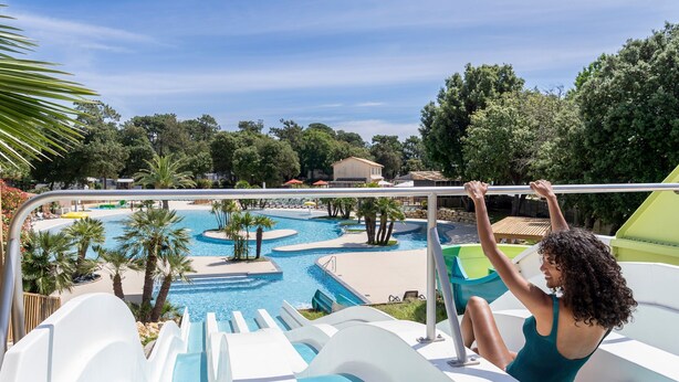A water slide at a resort with multiple pools and palm trees.