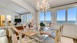 A dining area with a glass table, wicker chairs, and a chandelier. - 3 Bedroom/3Bath Oceanfront PentHouse in Shipwatch (Fernandina Beach)