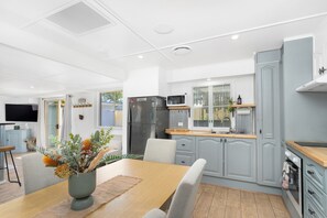 A modern kitchen with grey cabinets, a stainless steel refrigerator, and a microwave. - Spitaki (Nelson Bay)