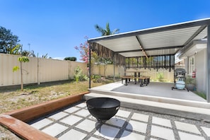 Un espacio cubierto con patio, una parrilla, una mesa y sillas.