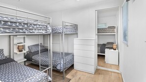 Een compacte, moderne slaapzaal met stapelbedden, een klein bureau en een garderobe.