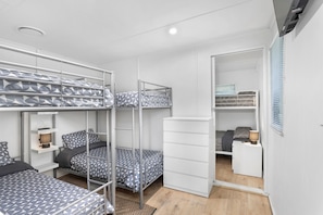 Habitación tipo dormitorio compacta y moderna, con literas, un escritorio pequeño y un armario.