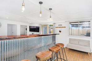 Una cocina moderna con una isla central, taburetes de bar e iluminación colgante.