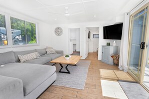 A modern living room with a grey sofa, wooden coffee table, and a television mounted on the wall.