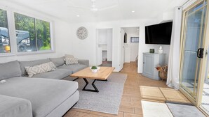 Un salon moderne avec un canapé gris, une table basse en bois et un téléviseur fixé au mur.