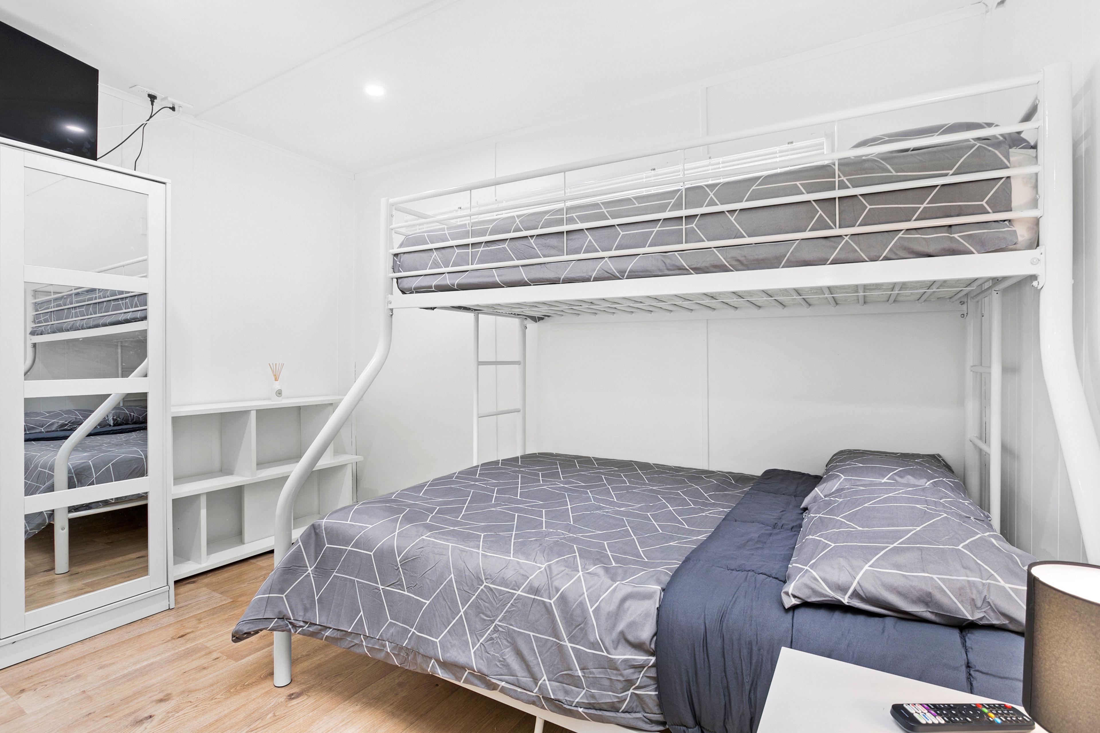 A bunk bed room with a desk and a lamp.