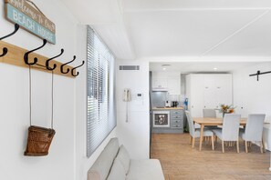 A modern interior with a wooden coat rack, a wicker basket, and a dining area with a table and chairs. - Spitaki (Nelson Bay)