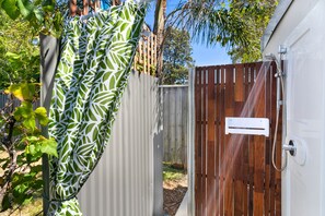 A gated area with a wooden door and a metal gate, surrounded by foliage and a wooden fence. - Spitaki (Nelson Bay)
