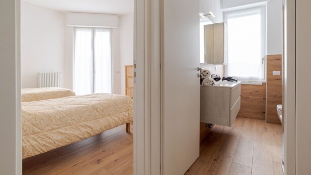Quarto com cama, mesa de cabeceira e janela.