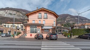 Um edifício de dois andares com uma varanda no segundo andar, um letreiro de 'Tobacco' e uma faixa de pedestres na frente.