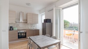 Cozinha moderna com área de refeições, forno embutido e vista através de uma porta de correr de vidro.