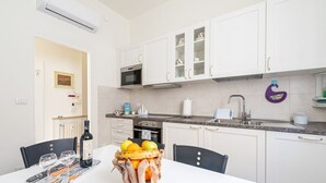 A modern kitchen with white cabinets, a microwave, and a sink. There is a fruit basket on the table with oranges and lemons. - GuestHost - Comfortable apartment located on the mezzanine floor of a building, with five floors in total, from the 70s. There are steps to access it (NO lift).In 85 m2 of space it accommodates 5 guests.We are in a very lively neighborhood, where the cit (Parma)