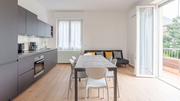 A modern apartment with a kitchen, dining area, and a balcony.