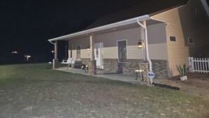 A two-story building with a covered porch and a stone foundation. - Lake Cabin, Fishing Access, swimming, walk to lake, boat parking, fenced yard!  (Nancy)