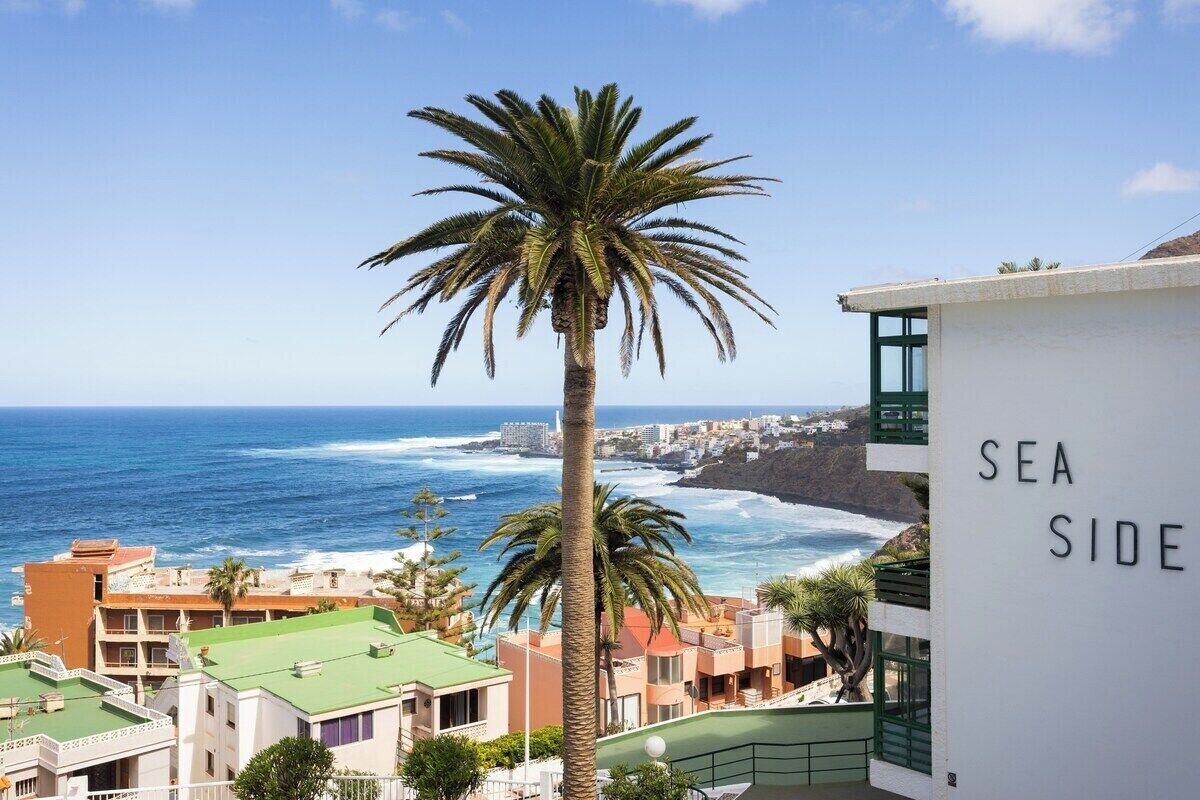 Edificio costiero con insegna "SEA SIDE", affacciato su una spiaggia e vista sull'oceano.