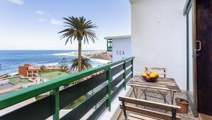 A balcony with a view of the sea, a wooden table with fruits, and a sign reading "SEA". - Home2Book Bright Sea Views Apartment & Pool (Bajamar)