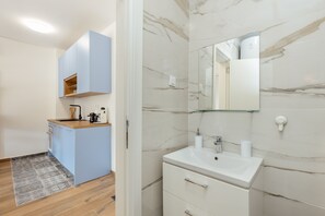 Enjoy a bathroom with a bathtub, sink, and kitchenette with a countertop.