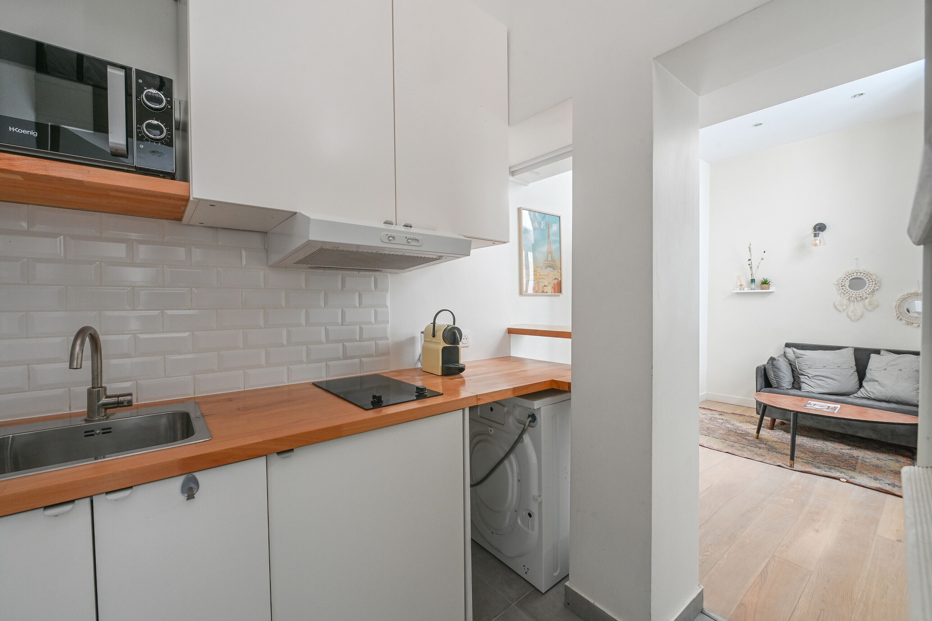 Een moderne keuken met witte kastjes, een houten aanrechtblad en een ingebouwde wasmachine.