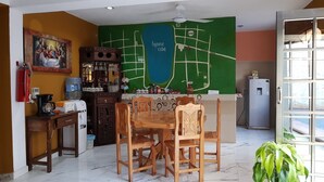 Un coin repas avec une table et des chaises en bois, un comptoir de cuisine avec divers objets, un réfrigérateur et une carte géographique accrochée au mur.