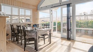 A dining area with a table set for four, wooden paneled walls, large windows, and a view of the outdoors. - 3 bedroom gorgeous home in Storvorde (Storvorde)