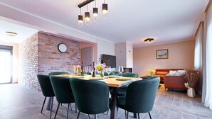 Un comedor con pared de ladrillo, un reloj y una lámpara moderna.