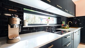 Una cocina moderna con armarios negros, encimera blanca y una cafetera.