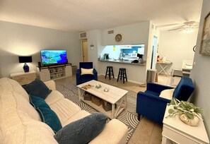 Una sala de estar con sofá, sillones, una mesa de centro y televisor.