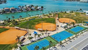 Un complexe sportif situé sur la côte, comprenant des terrains de baseball, des courts de tennis et une zone de plage.