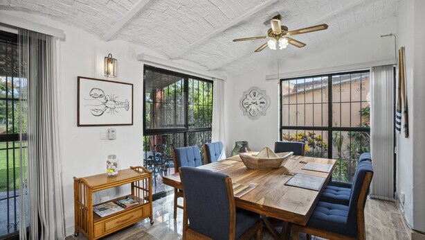 A dining area with a wooden table, blue upholstered chairs, and a ceiling fan.