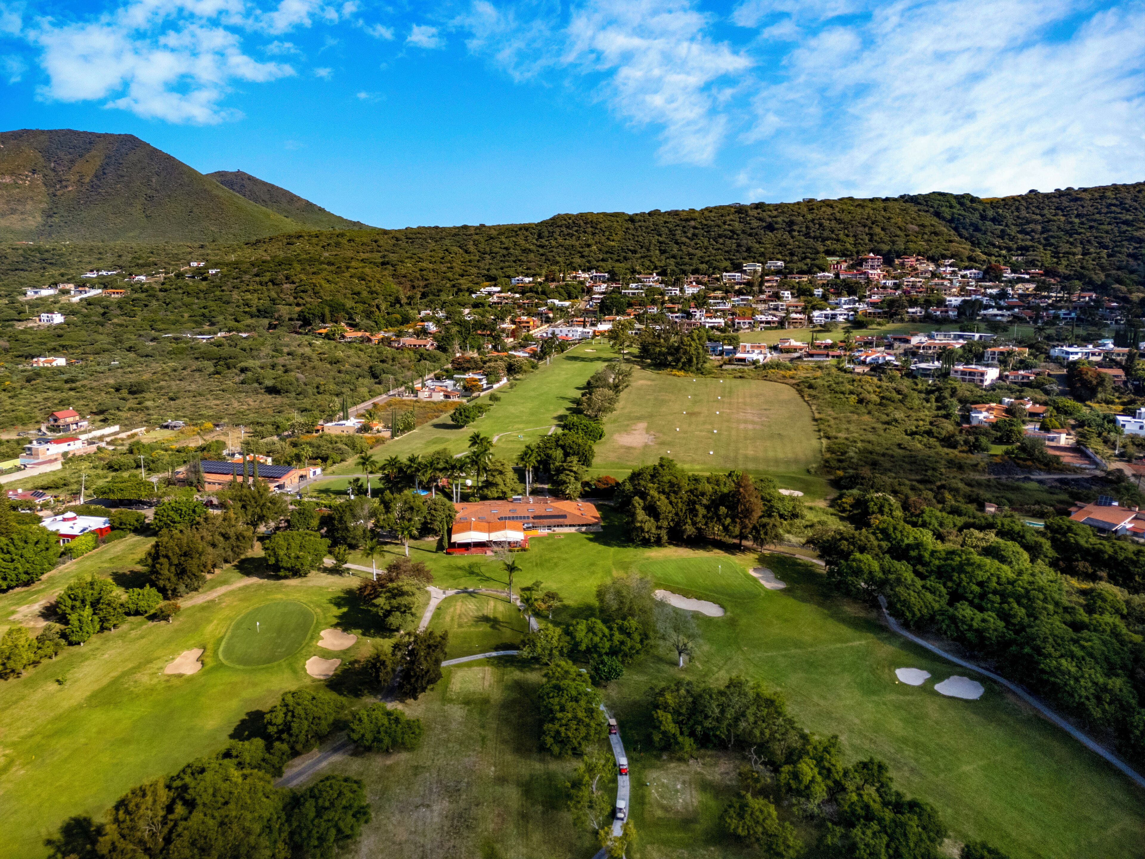 An aerial view of a residential area with houses, a golf course, and a mountain in the background.