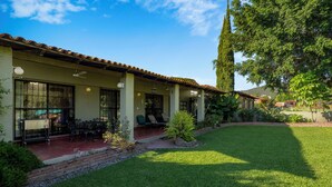 A two-story building with a patio area, outdoor seating, and a well-maintained lawn.