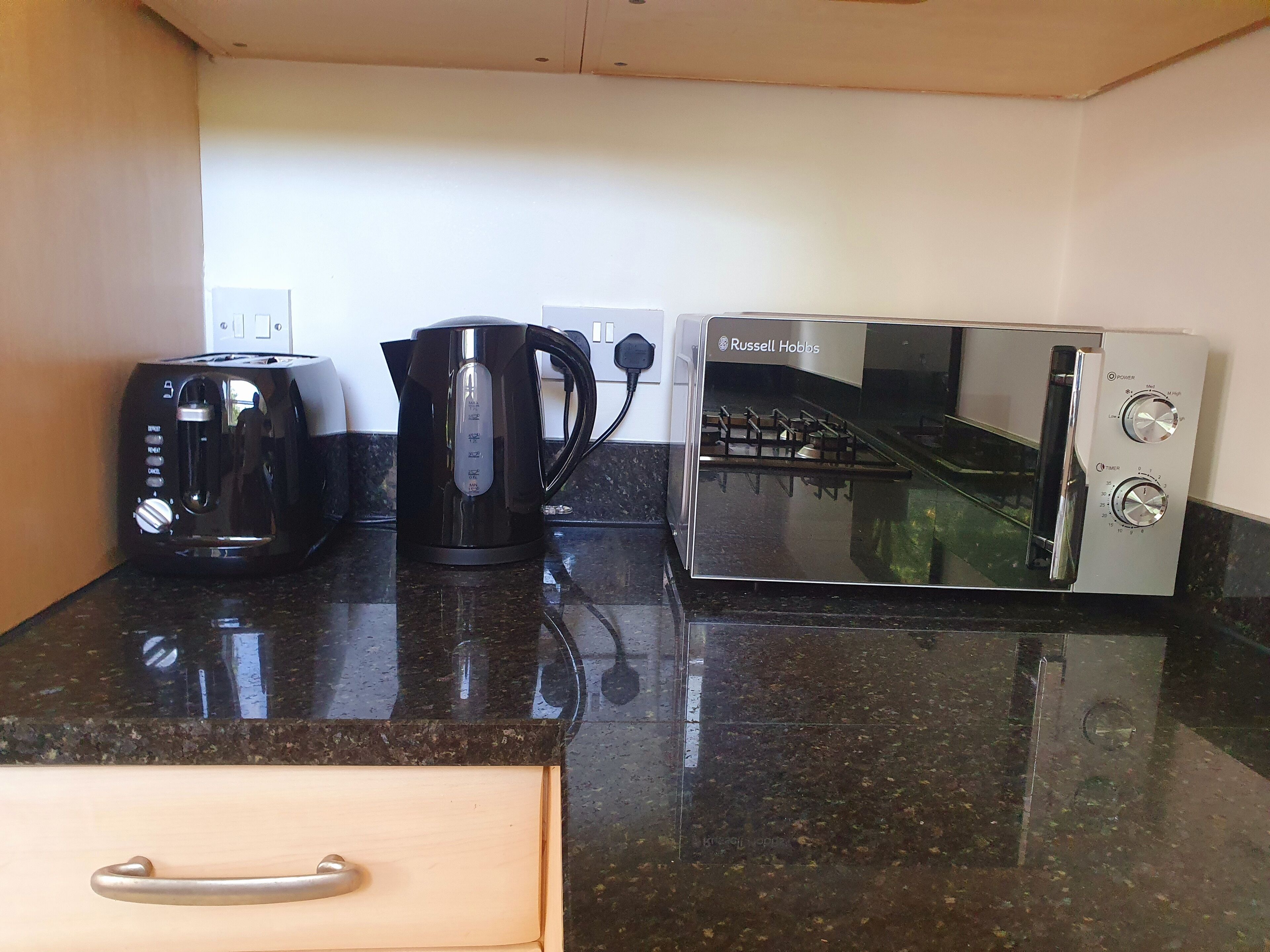 A kitchen with a toaster, kettle, and a microwave.