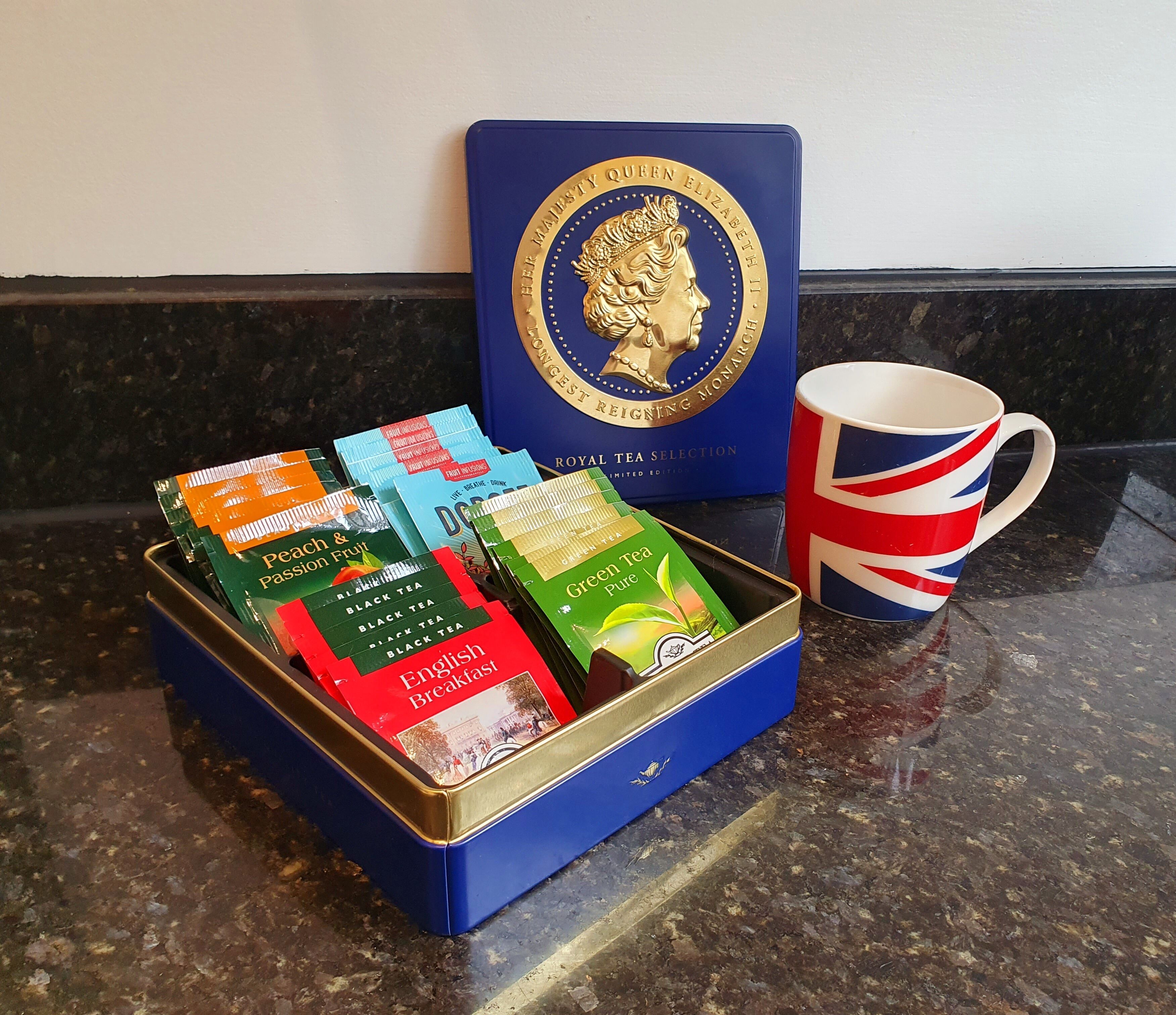 A blue box with tea packets and a Royal Tea Selection box, and a Union Jack mug on a countertop.