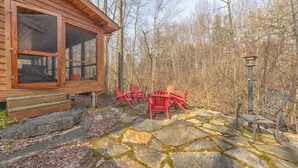 A wooden cabin with a stone patio, red Adirondack chairs, and a lantern post. - The Great Escape - Cabin with shared pool access and Goshorn Lake access (Saugatuck)